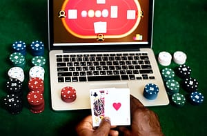 hand holding playing cards and playing casino on laptop
