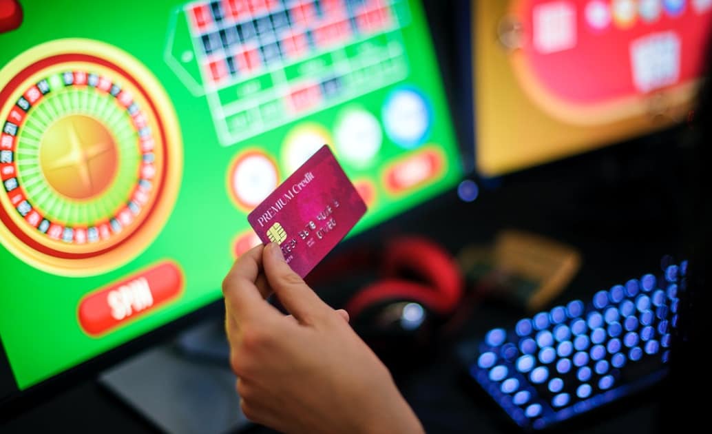 poker on monitor and a hand holding credit card